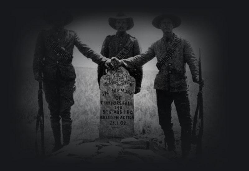 Three Australians stand over the grave of their comrade.