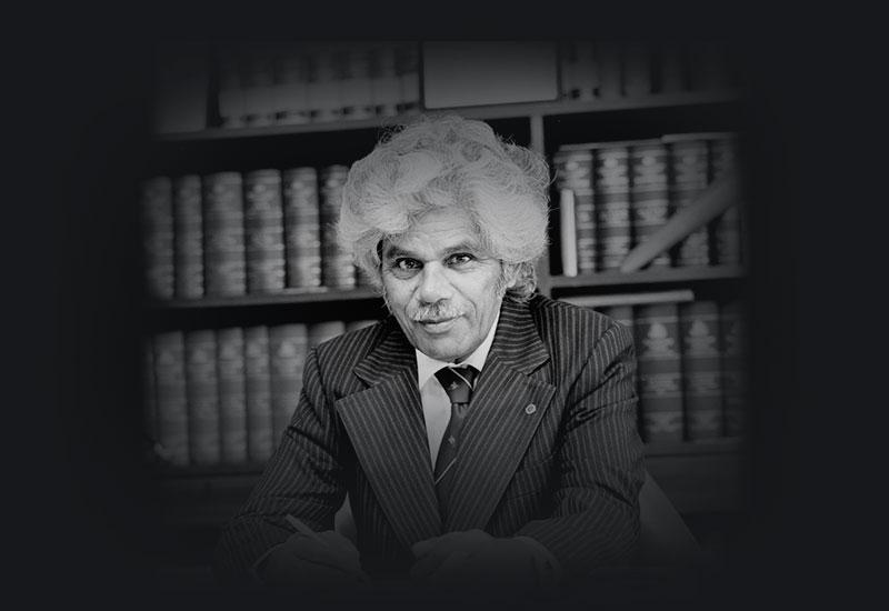 Senator Neville Bonner at his desk, wearing a pin-striped suit, 1979
