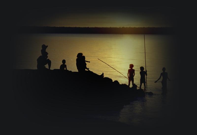 Silhouette of people fishing by the ocean 