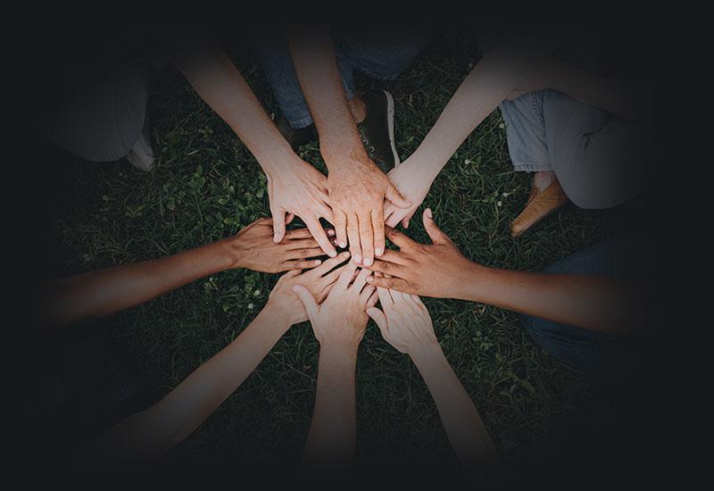 Eight people overlaying their hands 