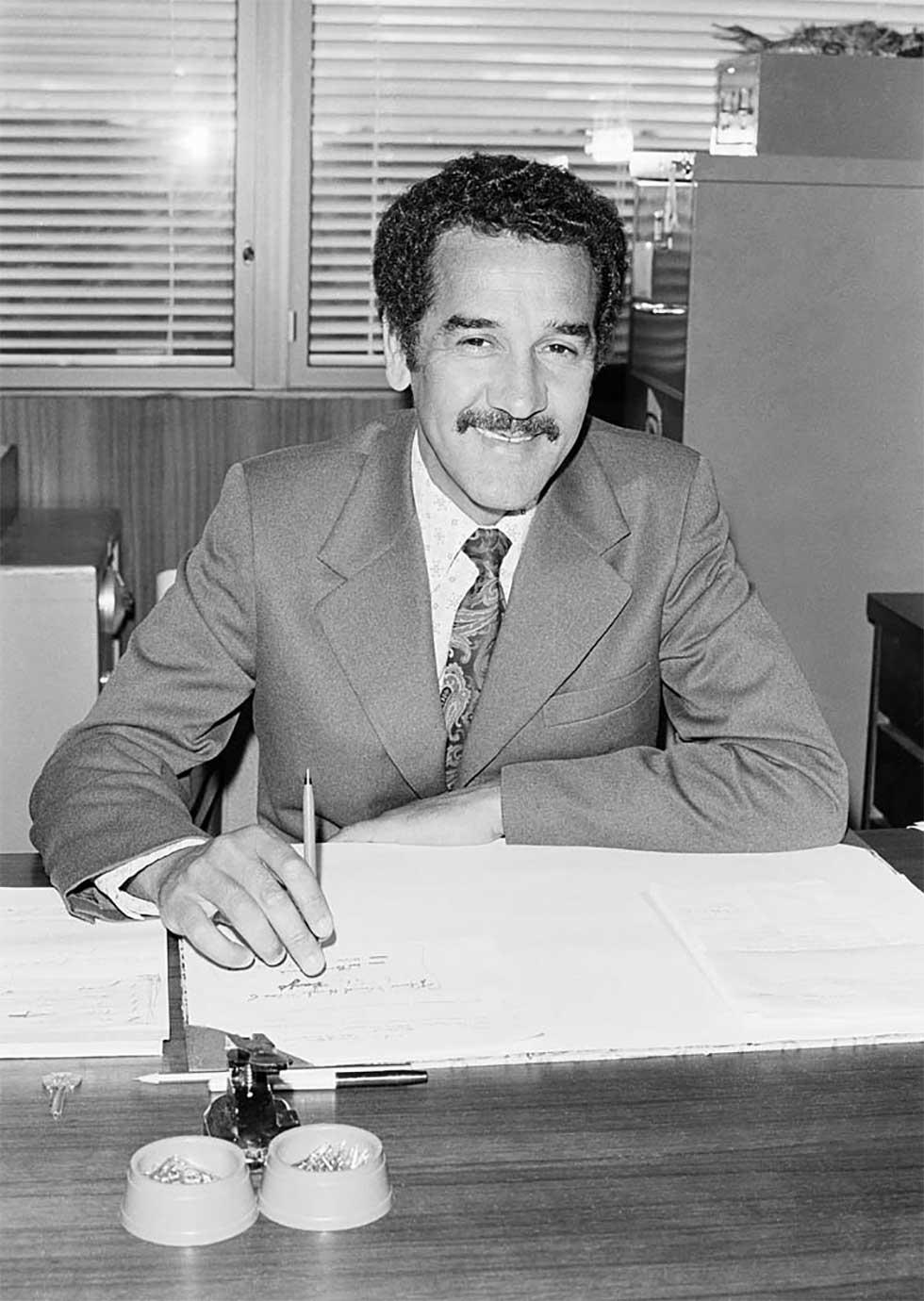 Charles Perkins seated behind his desk at the Department of Aboriginal Affairs.