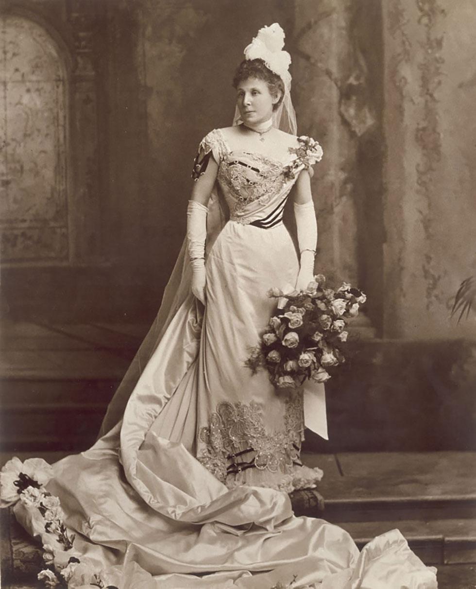 Jane Barton in a long white dress holding a bouquet.