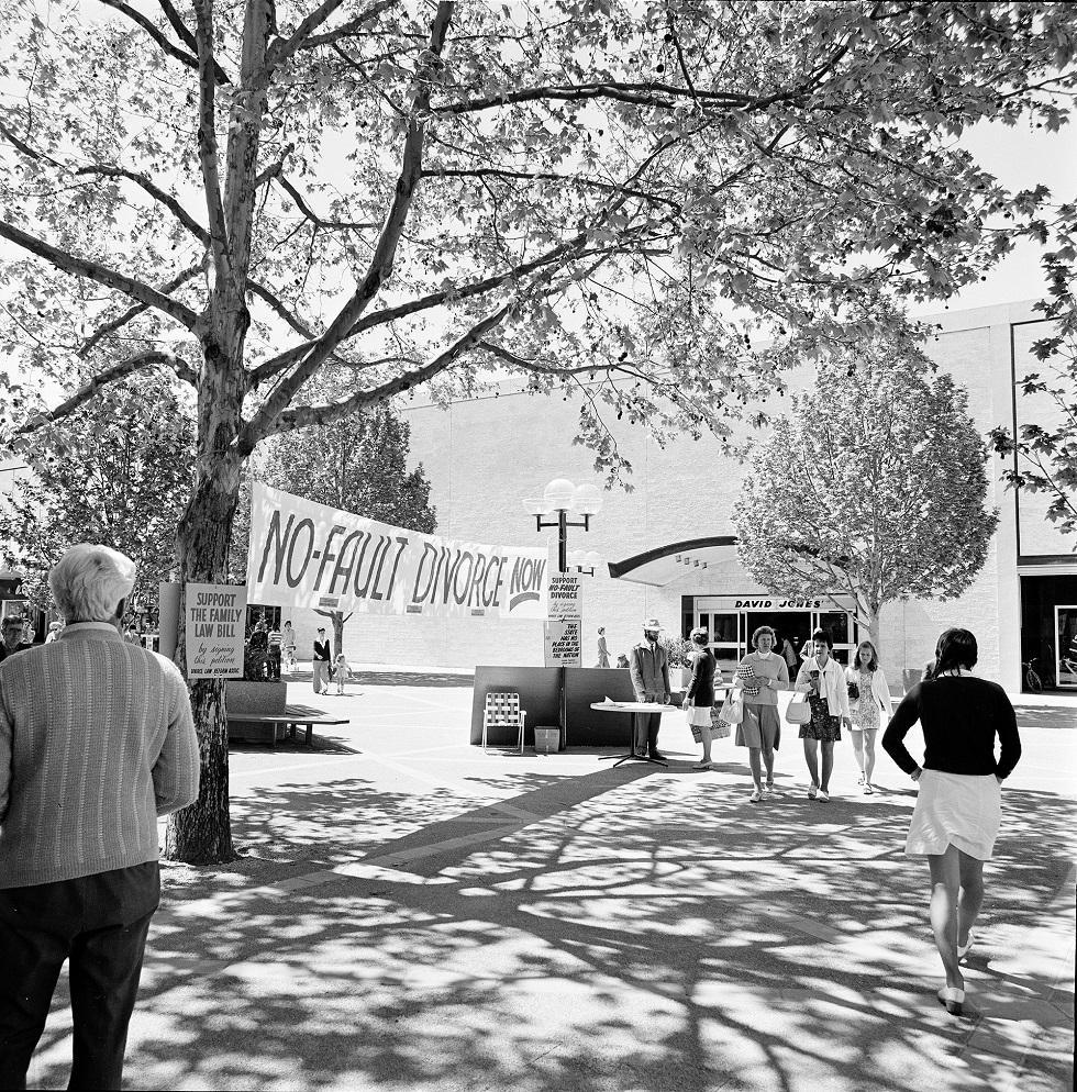 A sign reading ‘No-Fault Divorce’ hung between two trees in an outdoor pedestrian area in the city of Canberra.