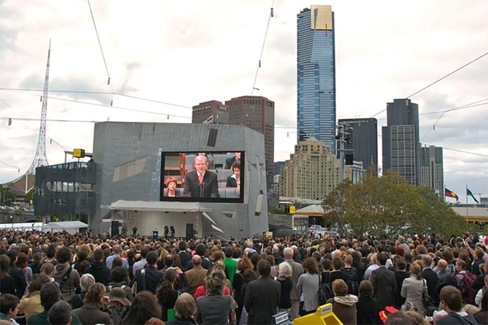 People watch the Prime Minister's speech on the big screen at Federation Square, Melbourne.