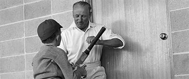 Sir Donald Bradman signing fan's cricket bat.
