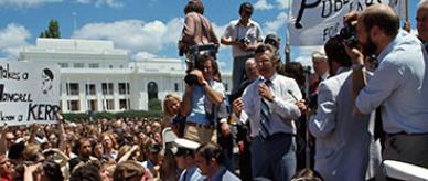 Bob Hawke surrounded by journalists and TV crew with Old Parliament House in the background.