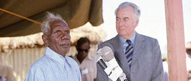 Vincent Lingiari standing behind a microphone with Gough Whitlam.