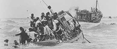 Two boats crowded with Vietnamese men, women and children in heavy seas.