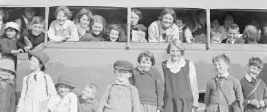 A group of school children standing beside a bus and looking out through the side windows. 