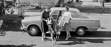 2 women with 2 dogs standing beside a Ford Cortina