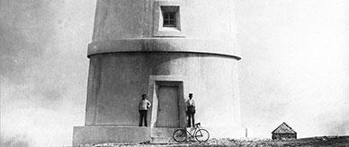 2 men and a bicycle at the door of a lighthouse