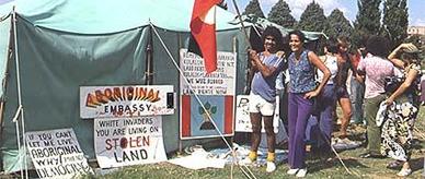2 people standing beside the Aboriginal Tent Embassy