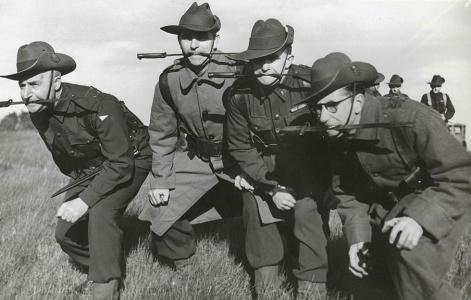 Four men of the Volunteer Defence Corps posing with daggers in their mouths