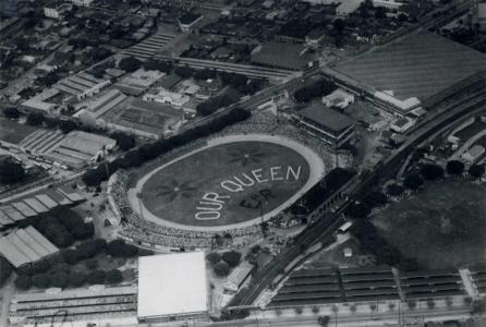 Aerial photo of children forming the words 'Our Queen' on an oval.