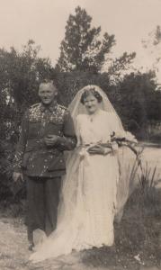 Wedding couple outside. He is wearing an Australian Army uniform and she is wearing a bridal gown and veil.