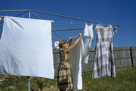A woman hanging sheets on a Hills Hoist clothesline. 