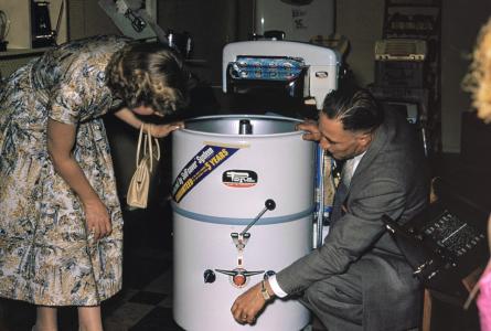 A man and a woman examine an appliance in a shop.