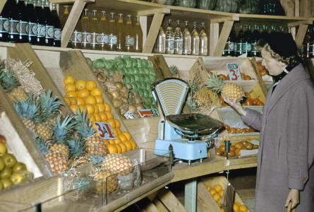A woman examining a pineapple in a fruit shop. 