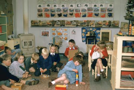 A group of children sitting and playing on the carpet in a classroom.