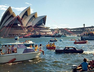 People on boats and an amphibious car in the harbour near Sydney Opera House.