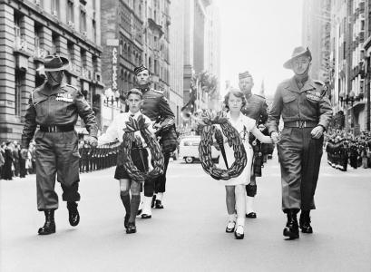 4 soldiers escorting 2 children who are both holding wreaths.